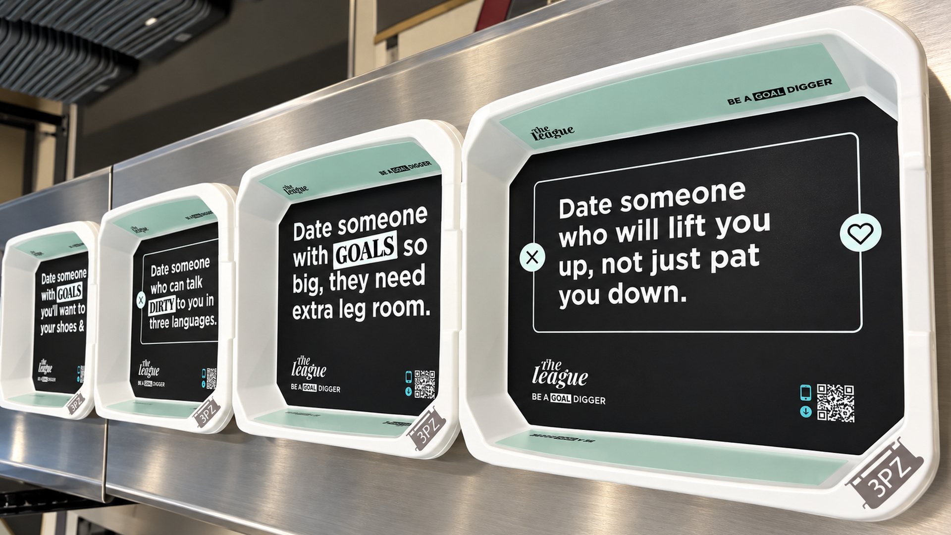 A row of League security trays at LAX, led by Date someone who will lift you up, not just pat you down.