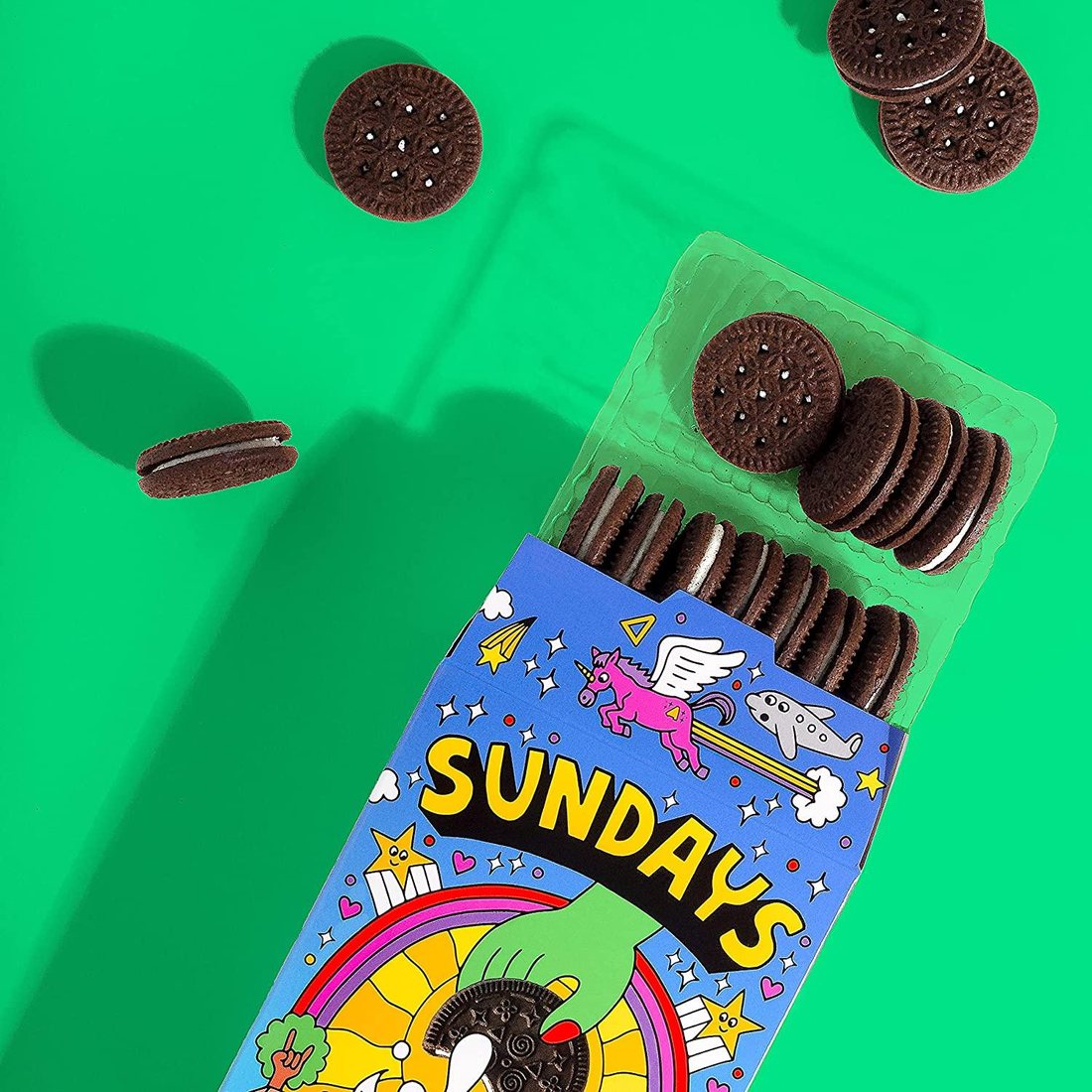 Open Sundays box on green, cookies spilling out past a flying unicorn and a smiling airplane