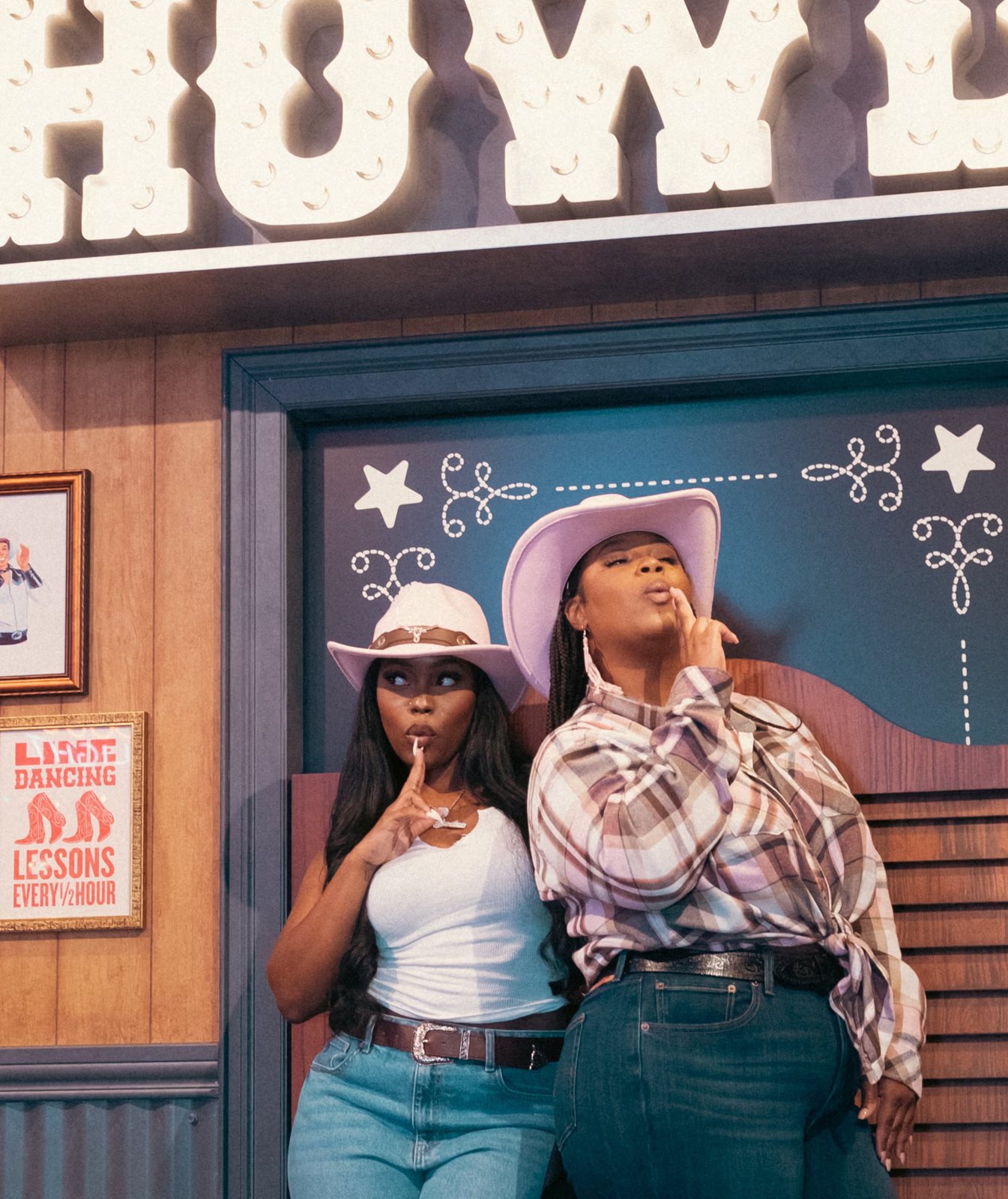 Two guests in cowboy hats posing in the Legends Saloon photo booth