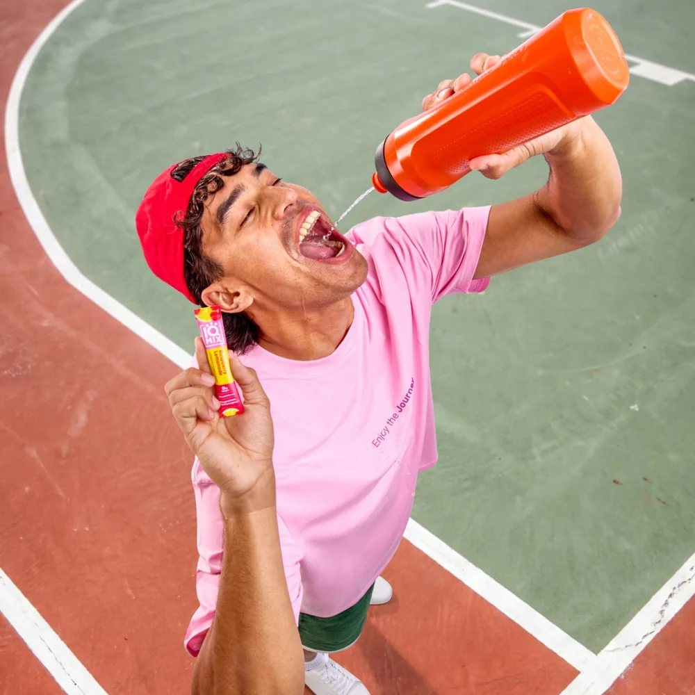Guy on a basketball court squirting water into his mouth, holding an IQMIX stick