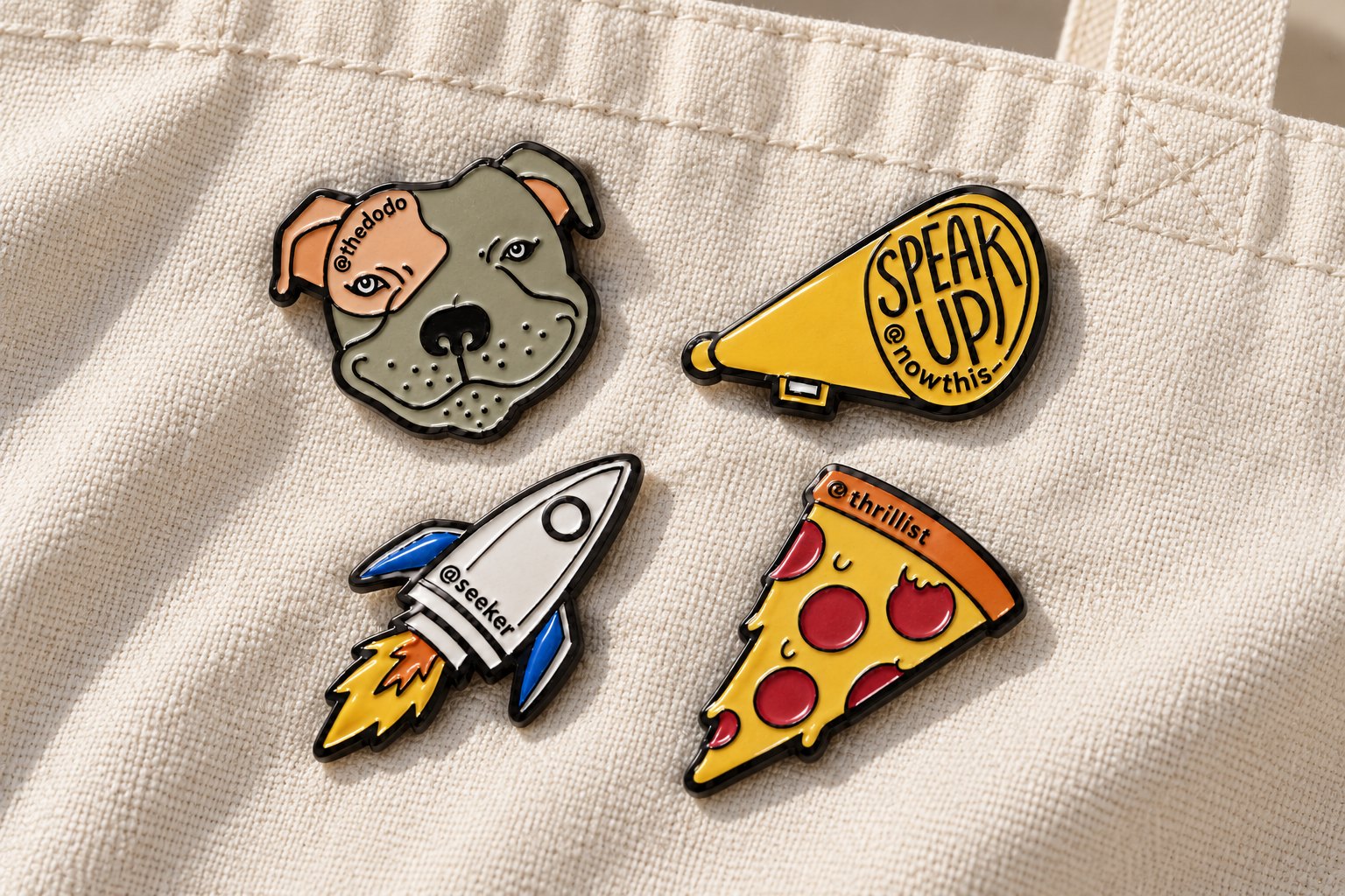 The Dodo, NowThis, Seeker, and Thrillist enamel pins on a canvas tote